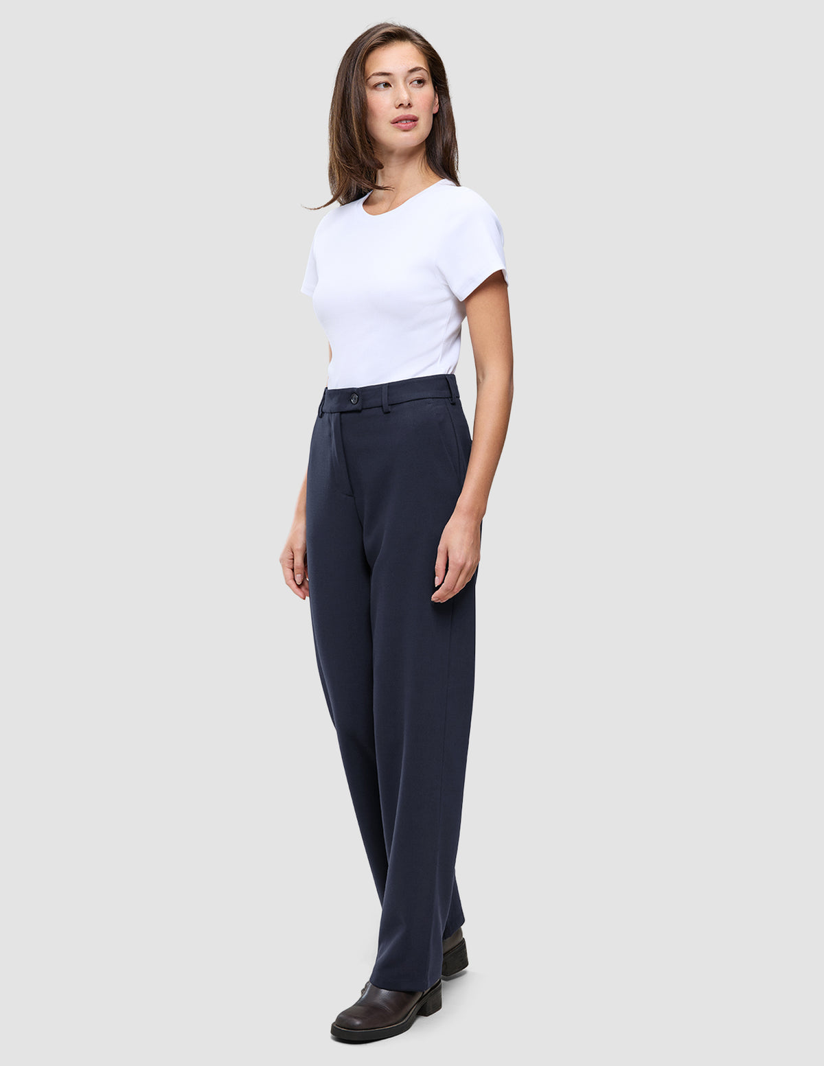 En kvinne iført en hvit T-skjorte og Women GO2 Pants Straight Blue Nights med rett ben.