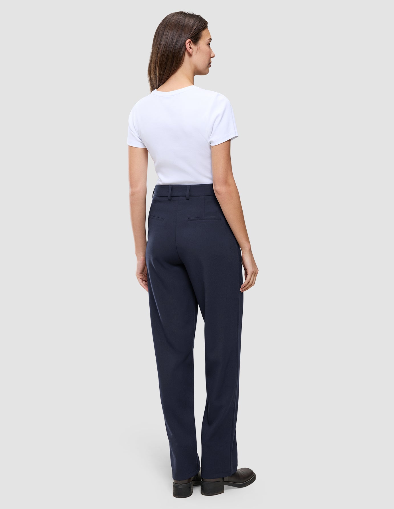 En kvinne iført en hvit T-skjorte og et par Women GO2 Pants Straight Blue Nights med høy midje og rette ben.