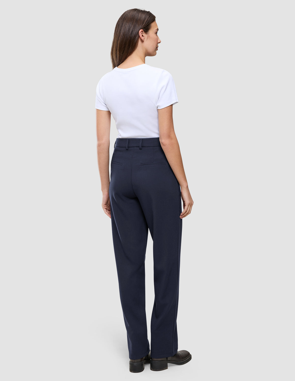 En kvinne iført en hvit T-skjorte og et par Women GO2 Pants Straight Blue Nights med høy midje og rette ben.