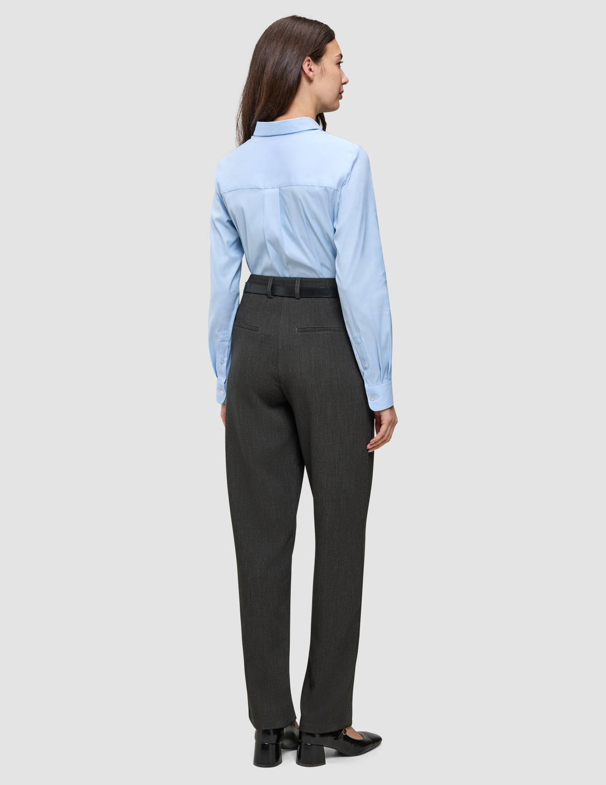 En person som har på seg en lyseblå skjorte med knapper, stappet inn i Women GO2 Pants Straight Dark Grey Melange, med et svart belte.
