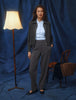 En kvinne har på seg en mørkegrå jakke, en lyseblå skjorte med knapper og Women GO2 Pants Straight Dark Grey Melange.