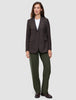 En kvinne i en brun blazer med smale striper, hvit T-skjorte, Women GO2 Pants Straight i fargen Dusty Olive og mørke loafers.