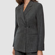 En kvinne iført en Women Nara Blazer Fitted Black Check – en skreddersydd blazer i kullgrått med dobbeltspent knappestolpe og rutemønster.