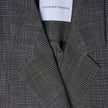 Nærbilde av en svart- og hvitrutet Women Nara Blazer Fitted Black Check med et SHAPING NEW TOMORROW-merke i nakken.