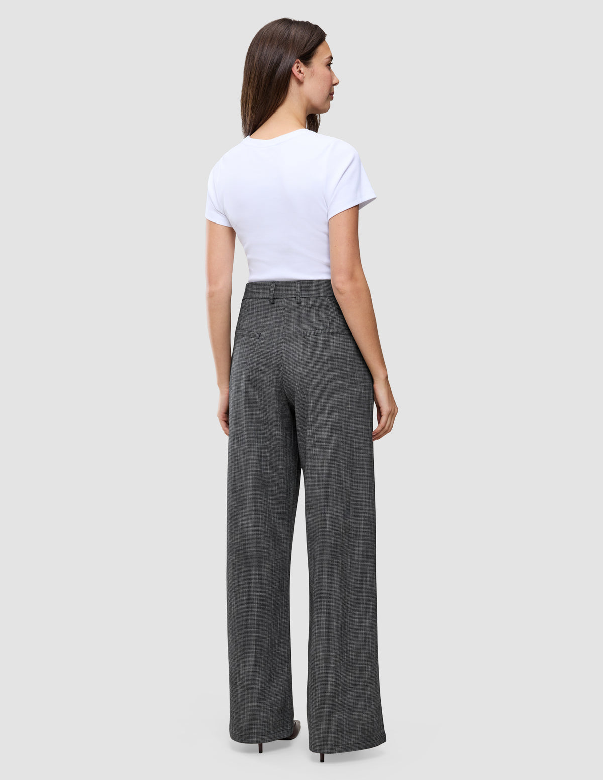 En person sett bakfra, kledd i en hvit T-skjorte og Women Nara Pants Wide Black Check med et diskret rutemønster.