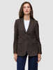 En kvinne har på seg en Women Serene Blazer Regular Walnut Herringbone over en hvit T-skjorte og blå jeans.