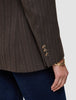 Nærbilde av en brun Women Serene Blazer Regular Walnut Herringbone-jakke med tre knapper på ermet og et gullarmbånd.