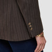 Nærbilde av en brun Women Serene Blazer Regular Walnut Herringbone-jakke med tre knapper på ermet og et gullarmbånd.