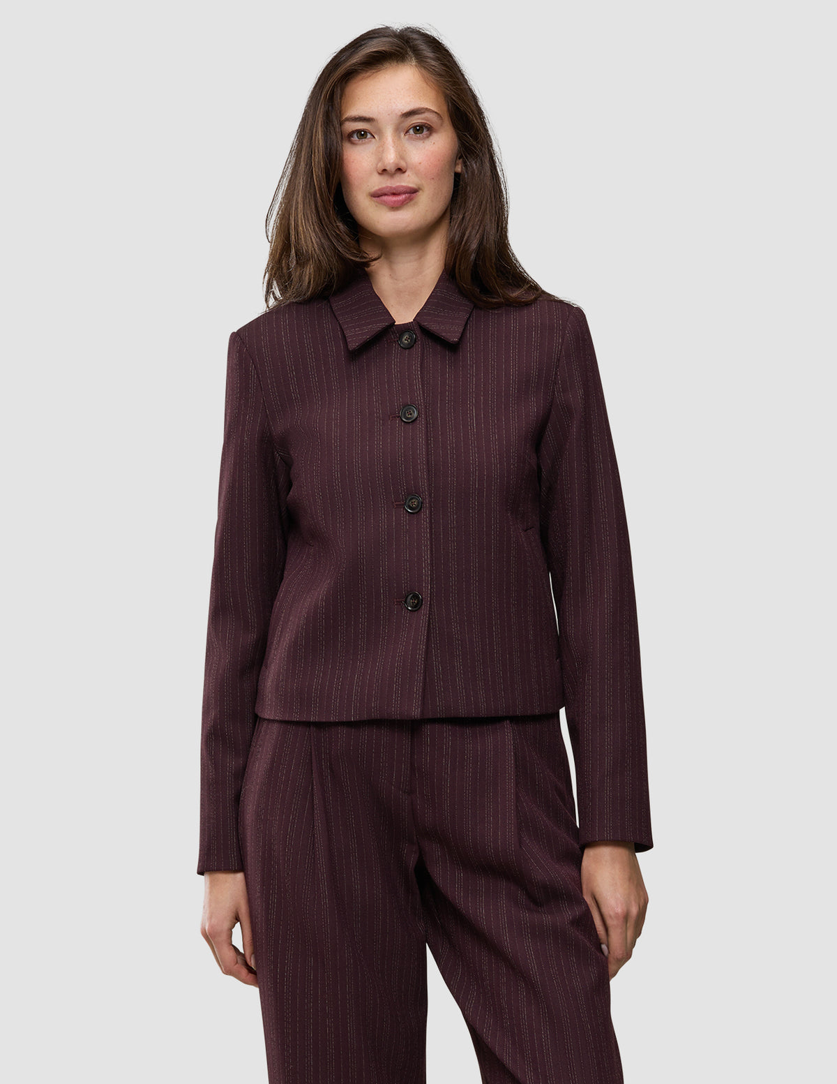 En kvinne iført en Women Serene Short Jacket Berry Pinstripe, med et minimalistisk design og knappelukking.