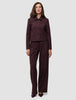 En kvinne har på seg en Women Serene Short Jacket Berry Pinstripe sammen med matchende bukser med vide ben i mørkt stoff med tynne striper.