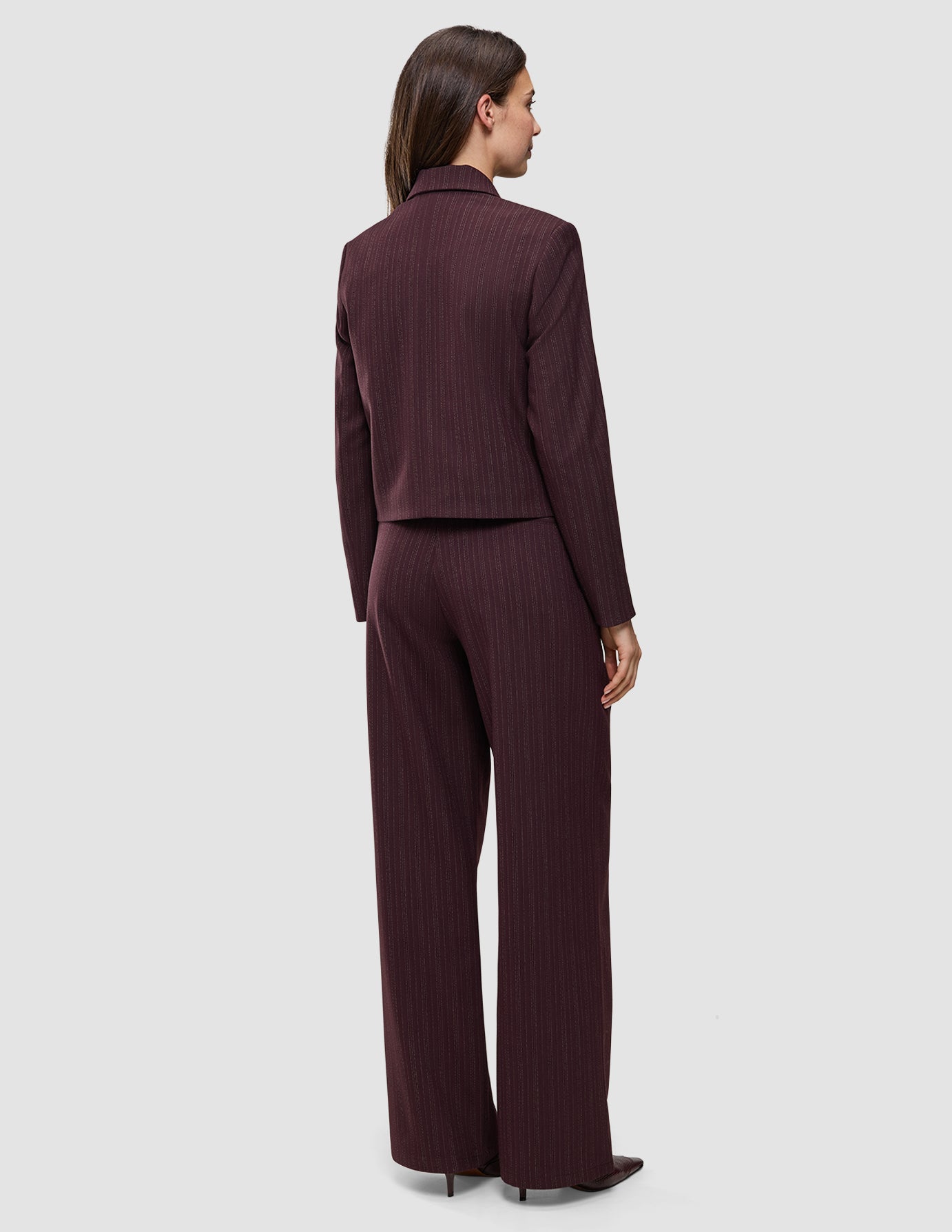 En person sett bakfra, kledd i en Women Serene Short Jacket Berry Pinstripe med matchende bukser med vide ben.